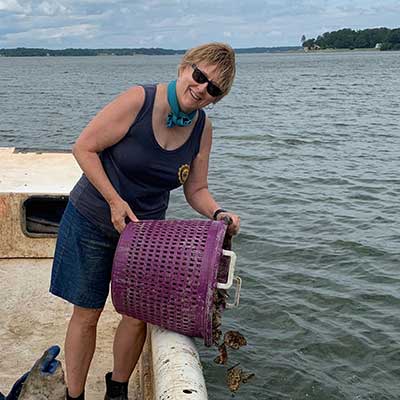Cindy Andrews dumping oyster shells into a body of water