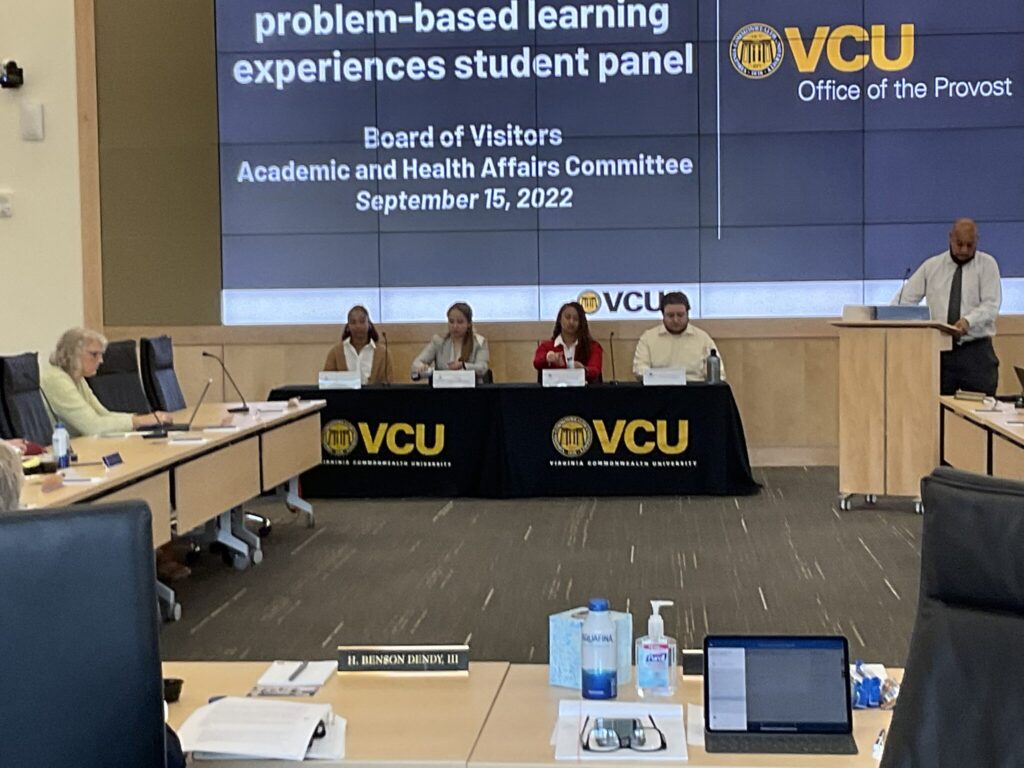 Four people siting a table with VCU logo in gold on a black tablecloth